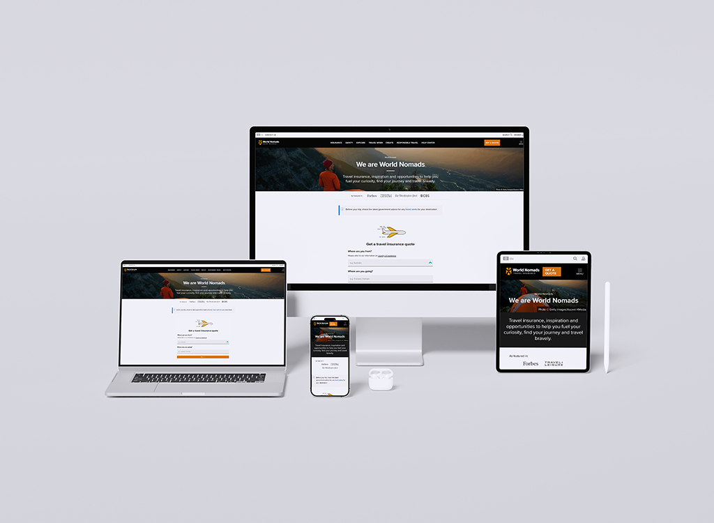 Image showcasing multiple devices displaying the World Nomads website, featuring travel insurance information and resources. The devices include a desktop monitor, laptop, tablet, and smartphone, highlighting the responsive design of the website aimed at travelers seeking safety and adventure.